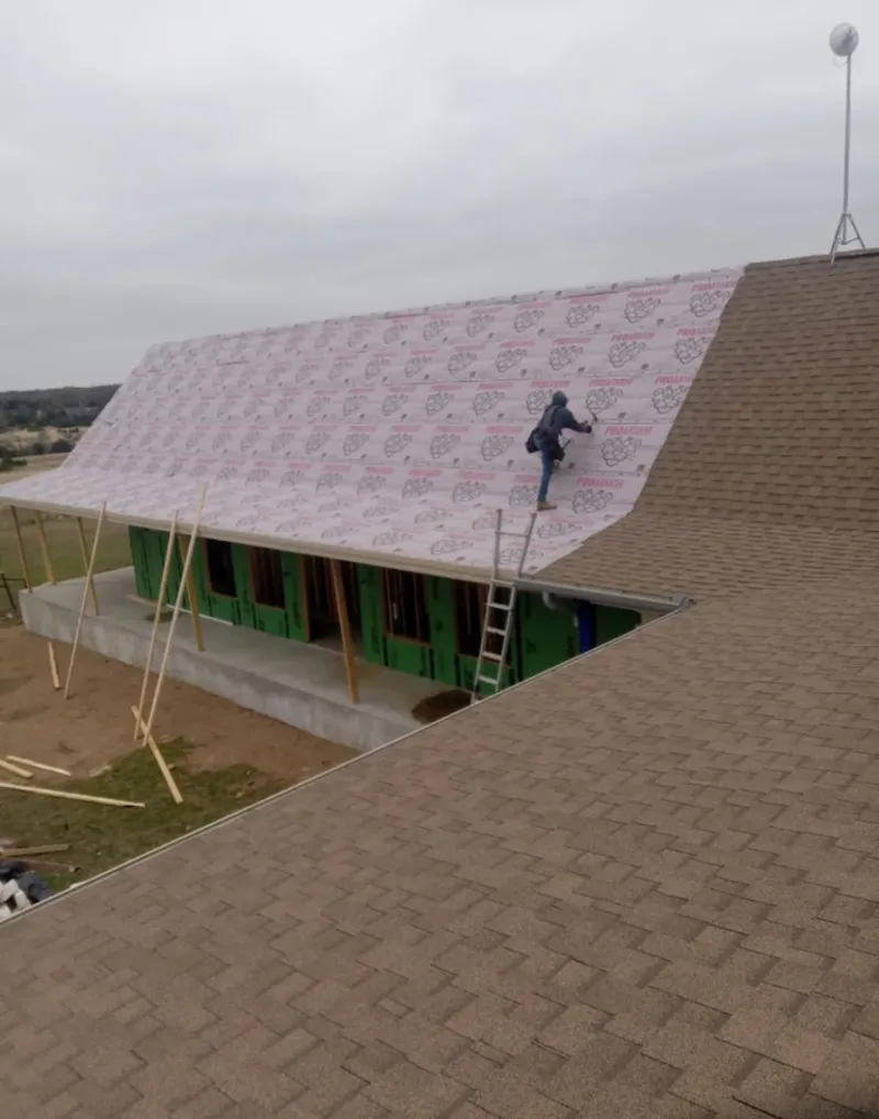 Worker preparing underlayment for a metal roof installation in Kokomo